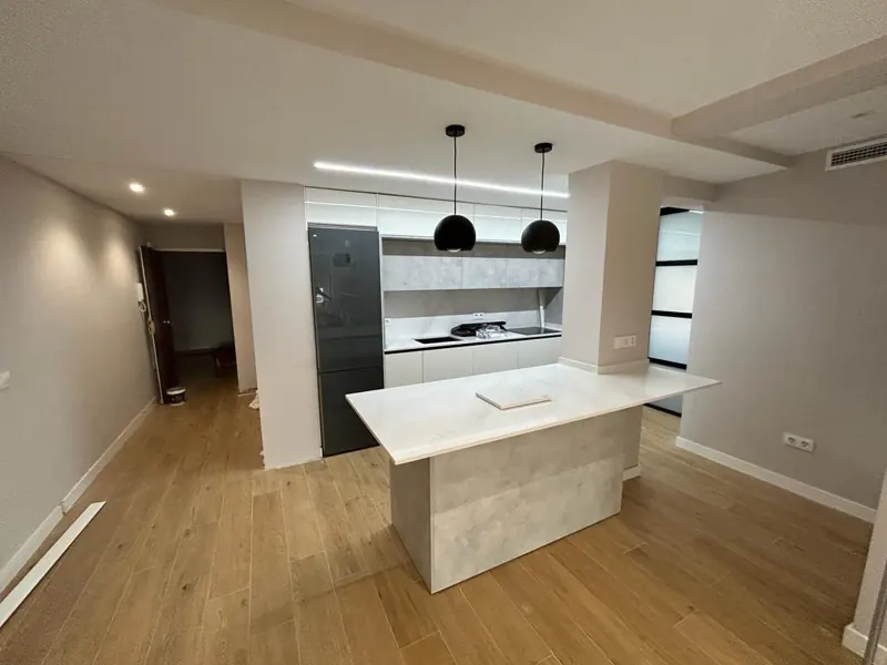 Cocina abierta al salón con isla de mármol y lámparas negras