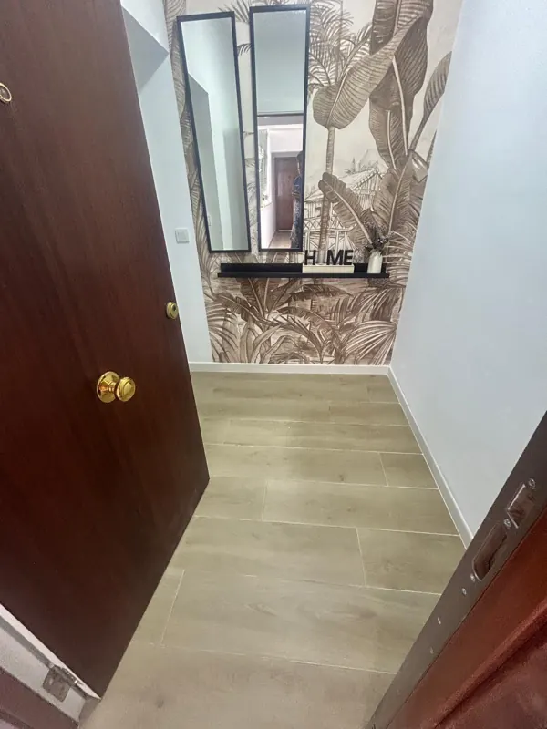 Puerta de entrada de madera y recibidor con suelo laminado y papel pintado tropical