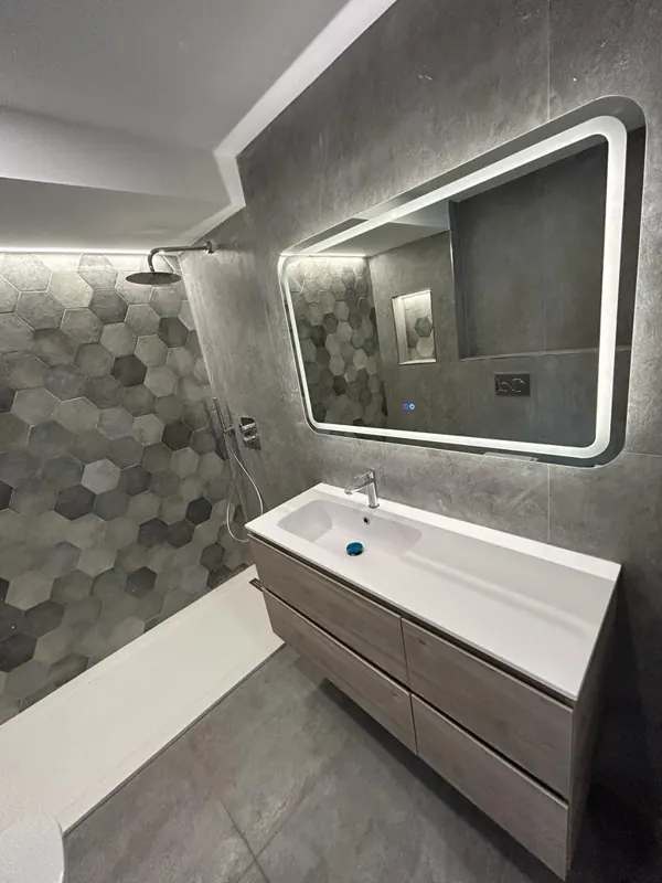 Baño reformado en Córdoba con ducha, azulejo hexagonal gris y mueble de lavabo suspendido