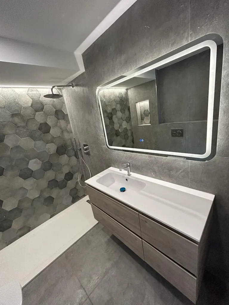 Baño reformado en Córdoba con ducha, azulejo hexagonal gris y mueble de lavabo suspendido