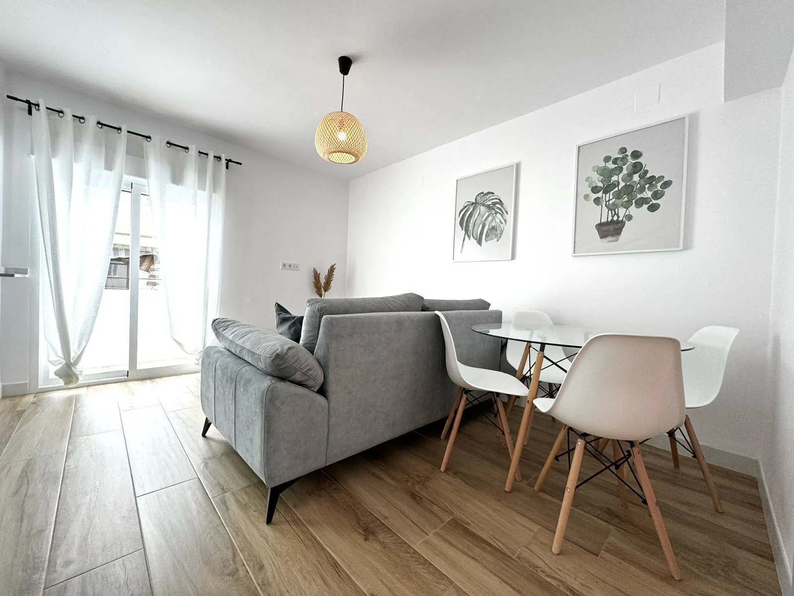Salón y cocina abierta tras una reforma integral en Córdoba, con sofá gris y suelo laminado
